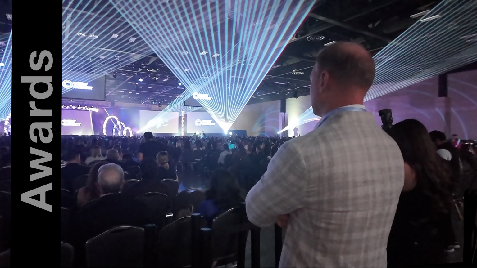 Blue and white laser beams spanning a packed ballroom above seated event guests